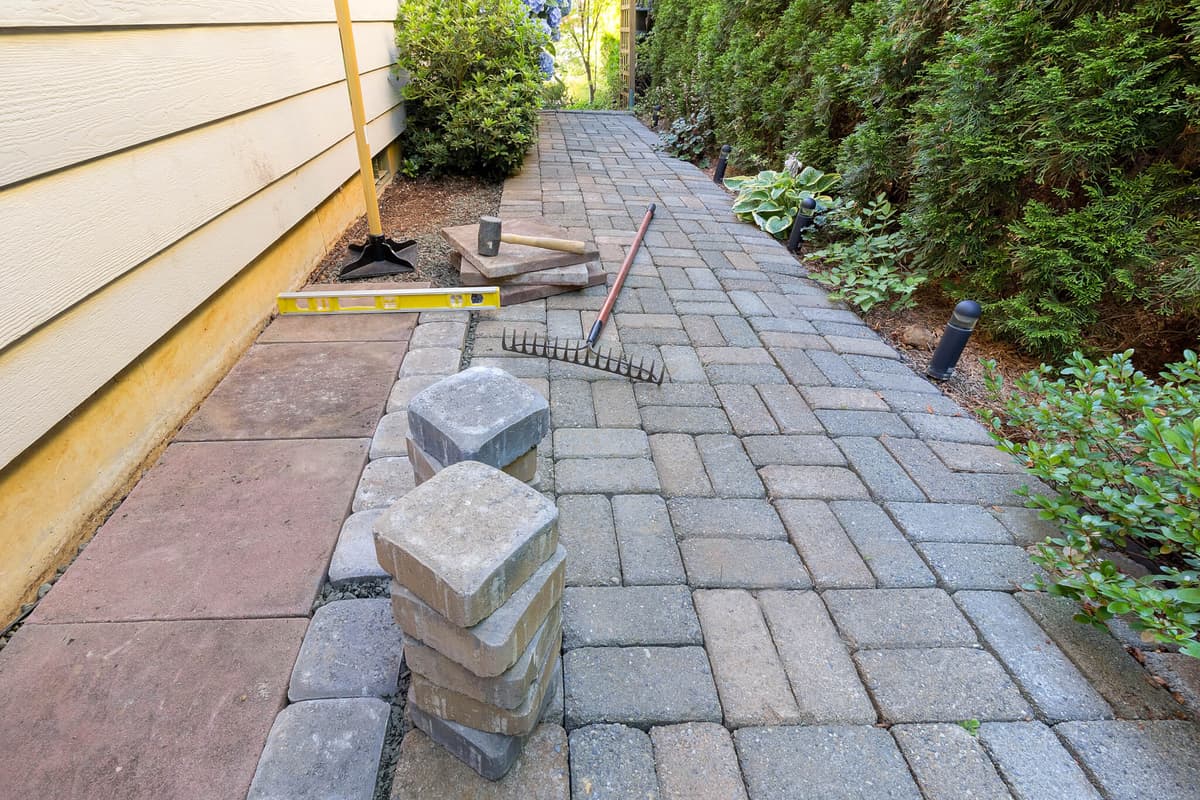 Paver walkway installation with brick pavers and leveling tools at a residential property in Lake Orion Michigan