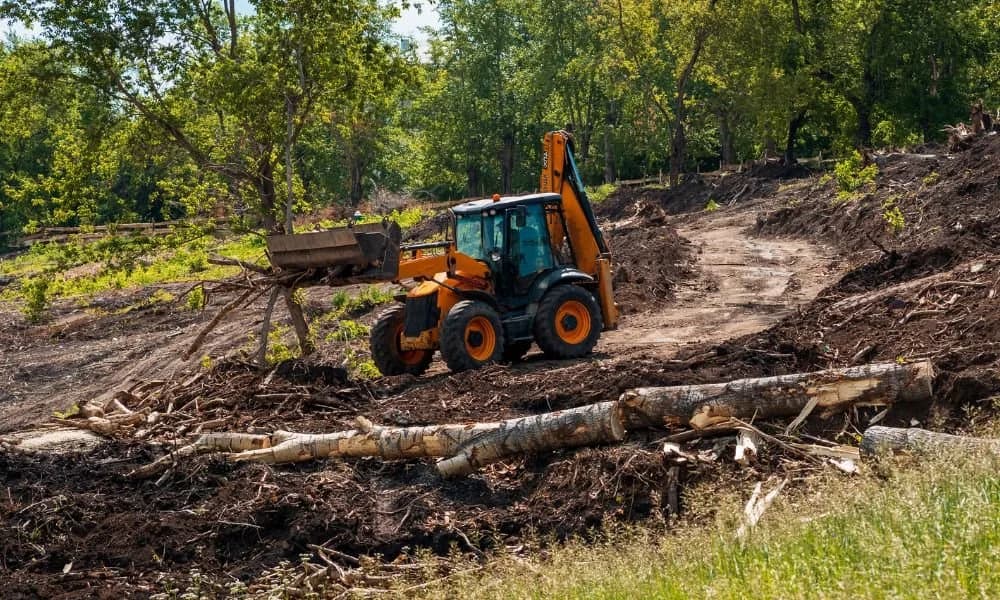 Heavy equipment clearing storm debris and fallen trees from a property in Orion Township MI